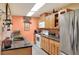A functional kitchen features tile backsplash, stainless steel refrigerator and granite counters with light wood cabinets at 2203 Starboard, Winter Haven, FL 33881