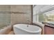 Close-up of modern standalone tub near a sunny window in a large, tiled bathroom at 3121 Highlands By The Lake Way, Lakeland, FL 33812