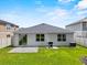 Rear view of a single-story home with a well-maintained lawn and small gravel patio at 546 Scott Lake Creek Ln, Lakeland, FL 33813