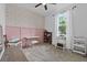 Bright bedroom features pastel pink wainscoting and wallpaper, complemented by a ceiling fan at 546 Scott Lake Creek Ln, Lakeland, FL 33813