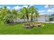 Beautiful front yard featuring lush green grass, tropical plants and a white brick house at 6 Rosewood Dr, Davenport, FL 33837