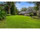 Wide shot of the backyard lawn, trees, and enclosed pool with screened enclosure at 6001 Sweet Gum Run, Bartow, FL 33830