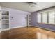 Cozy bedroom with purple walls, hardwood floors, built-in shelves, and a window with light-filtering blinds at 6001 Sweet Gum Run, Bartow, FL 33830