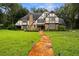 Charming Tudor-style home with a brick facade, lush green lawn, and a stone pathway leading to the front door at 6001 Sweet Gum Run, Bartow, FL 33830