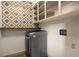A modern laundry room with a gray front-load washer and dryer, and white open shelving at 6001 Sweet Gum Run, Bartow, FL 33830