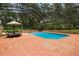 Enclosed pool with blue water, brick trim and surrounding trees at 6001 Sweet Gum Run, Bartow, FL 33830