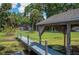 View from the dock showcasing the lake, lush green lawn, and beautiful brick house at 6281 Halabrin Rd, Haines City, FL 33844