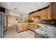 Well-lit kitchen featuring granite countertops, wooden cabinets, and stainless steel refrigerator at 6281 Halabrin Rd, Haines City, FL 33844