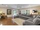 Spacious living room features hardwood floors, a ceiling fan, and a plush gray sectional at 6819 Broken Arrow S Trl, Lakeland, FL 33813