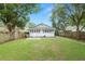 Expansive backyard featuring lush green grass, mature trees, and a charming light blue home exterior at 817 College Ave, Lakeland, FL 33801