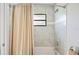 Bathroom features a tub with a beige shower curtain, showerhead, and a tiled wall with a small window at 818 Woodward St, Lakeland, FL 33803