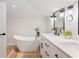 Bright bathroom with double sink vanity, soaking tub with black fixtures, and light wood-look floors at 818 Woodward St, Lakeland, FL 33803