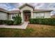 Charming home featuring a red double-door entry and well-maintained front yard landscaping with flower accents at 8323 Greystone Dr, Lakeland, FL 33810