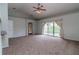 Spacious living room featuring neutral carpeting, sliding glass doors to backyard and a ceiling fan at 8323 Greystone Dr, Lakeland, FL 33810