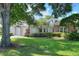 A well-maintained single-story home with a brick accents, mature trees, and lush green lawn at 1145 Denton St, Lakeland, FL 33803