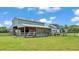 View of barn with covered storage and house in the background, situated on a lush green lawn at 1385 Ewell Rd, Lakeland, FL 33811