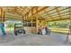 Spacious barn interior with wooden stalls, storage and a utility vehicle, set on a concrete floor at 1385 Ewell Rd, Lakeland, FL 33811