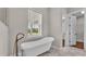 Bright bathroom featuring a soaking tub, marble floors, and view from the window at 1385 Ewell Rd, Lakeland, FL 33811