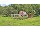 View of a classic red chicken coop with a secure, fenced run for fowl, set in a grassy area at 1385 Ewell Rd, Lakeland, FL 33811