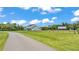 Expansive white farmhouse with a long driveway and large grassy field under a sunny sky at 1385 Ewell Rd, Lakeland, FL 33811