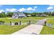 Gated entrance to a sprawling estate with a white farmhouse and lush green lawns under a blue sky at 1385 Ewell Rd, Lakeland, FL 33811