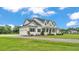 Elegant white farmhouse with a side-entry garage, lush lawn, and beautifully landscaped grounds at 1385 Ewell Rd, Lakeland, FL 33811