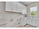 Bright laundry room with white cabinets, marbled floor tiles, and a window overlooking lush greenery at 1385 Ewell Rd, Lakeland, FL 33811