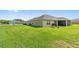 Back exterior view of the property with a screened in patio, expansive grassy area and sunny sky at 1531 Blue Sky Blvd, Haines City, FL 33844