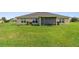 Back exterior view of the property features a screened in patio and spacious grassy area at 1531 Blue Sky Blvd, Haines City, FL 33844