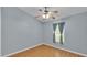 This bedroom features hard wood floors, blue-grey walls, a window, and a ceiling fan at 1746 Grey Fox Dr, Lakeland, FL 33810