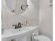 Neat bathroom features a pedestal sink, dark faucet, toilet, and a round mirror at 1910 Clubhouse Rd, Lakeland, FL 33813