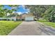 A long driveway leading to a home featuring a two-car garage and well-kept landscaping at 1910 Clubhouse Rd, Lakeland, FL 33813