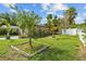Landscaped yard with trees including palms, lawn, and a partial fence at 1927 E Main St, Lakeland, FL 33801