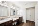 Bathroom with dual sinks set in granite countertop vanities, accompanied by modern lighting fixtures and wood-look tile floors at 2110 Bristol Ave, Lakeland, FL 33803