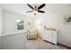 Bright Bedroom with neutral decor, featuring a white crib, glider chair, and a dresser under a ceiling fan at 2110 Bristol Ave, Lakeland, FL 33803