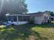 View of rear exterior with screened porch, grassy area, and mature landscaping at 2424 Bates Sw Ave, Winter Haven, FL 33880