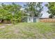 View of the green backyard with a small green home and wood fence at 2711 Crutchfield Rd, Lakeland, FL 33805