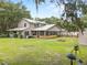 Large grassy backyard featuring the rear of the home and a stone fire pit at 2911 Walker Rd, Lakeland, FL 33810