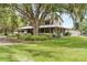 Beautiful front yard featuring green grass, mature trees, lush landscaping and a charming wraparound porch at 2911 Walker Rd, Lakeland, FL 33810