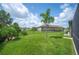 Lush backyard with a vibrant green lawn, bordered by mature trees and a charming black metal fence at 4124 Prima Lago Cir, Lakeland, FL 33810