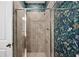 Modern shower with tiled walls and a sleek glass door, complemented by floral wallpaper at 4124 Prima Lago Cir, Lakeland, FL 33810
