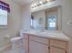 Bathroom features a white sink and cabinet, a toilet, a large mirror and a window with purple decor at 4926 Pleasant Hollow Trl, Lakeland, FL 33811