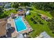Aerial view of a large community pool surrounded by lounge chairs, shaded seating, and lush landscaping at 4926 Pleasant Hollow Trl, Lakeland, FL 33811