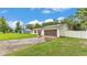 Charming single-story home with a well-maintained lawn, white fence, and modern solar panels at 5316 Forestbrook E Dr, Lakeland, FL 33811