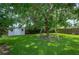 Spacious backyard with a large shade tree, swing set, storage shed, and well-maintained lawn, ideal for Gathering enjoyment at 5619 Stratford Ln, Lakeland, FL 33813
