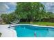 Backyard swimming pool with a hammock, a slide and a diving board, surrounded by a well-kept lawn at 5619 Stratford Ln, Lakeland, FL 33813