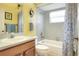 A cheerful bathroom with a yellow wall, a blue shower curtain, and a vanity at 5857 Macaw Pl, Lakeland, FL 33809