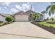 Inviting single-story home with a two-car garage, manicured lawn, and a decorative palm tree at 6001 Condor Dr, Lakeland, FL 33809