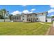 Backyard view of house with screened-in pool, white fence, balcony, manicured lawn and concrete pathway at 619 Somerset Loop, Auburndale, FL 33823