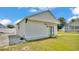 Garage featuring white siding, green trim, concrete pathway, and well-maintained lawn at 619 Somerset Loop, Auburndale, FL 33823